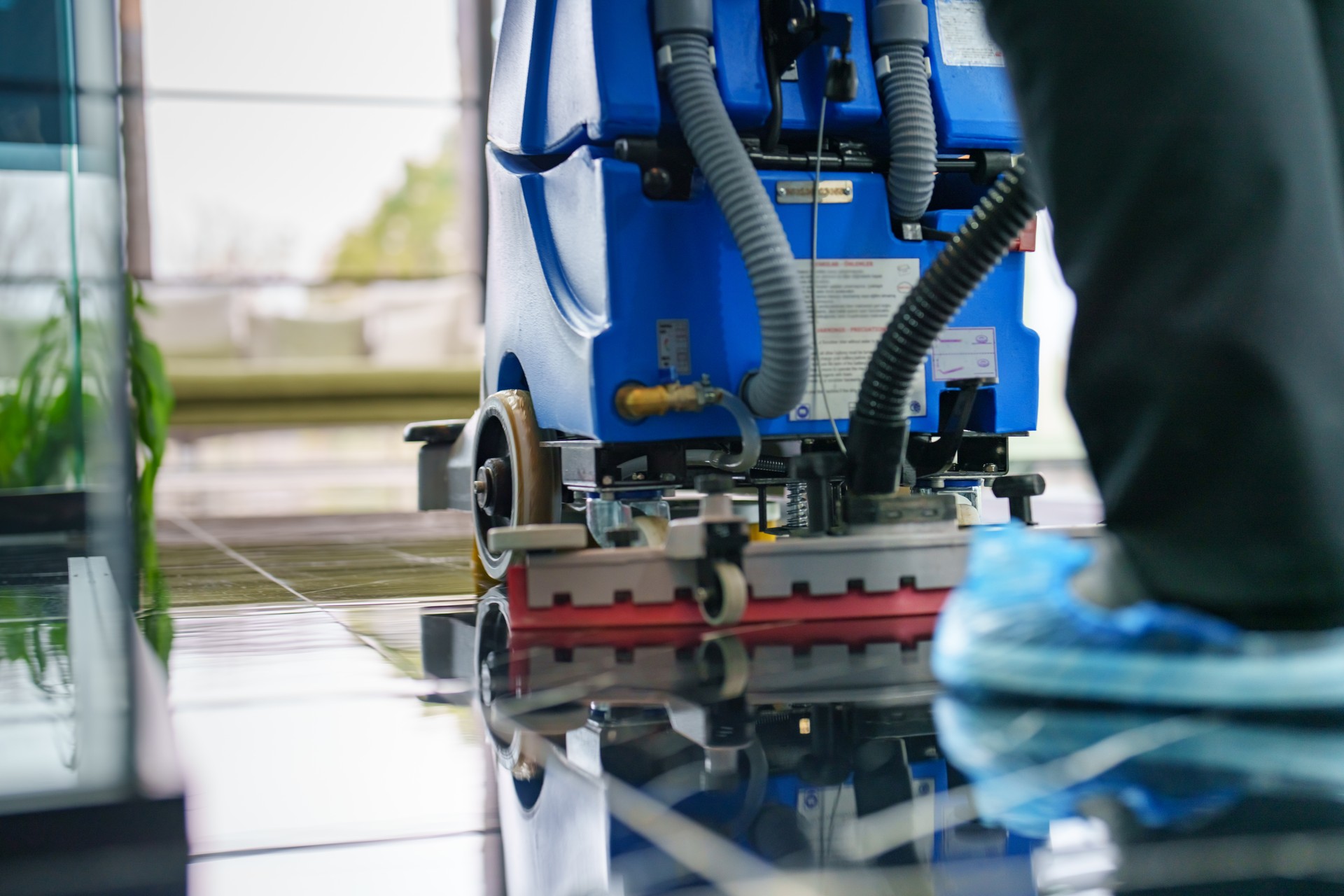 Female worker cleaning office lobby floor with machine